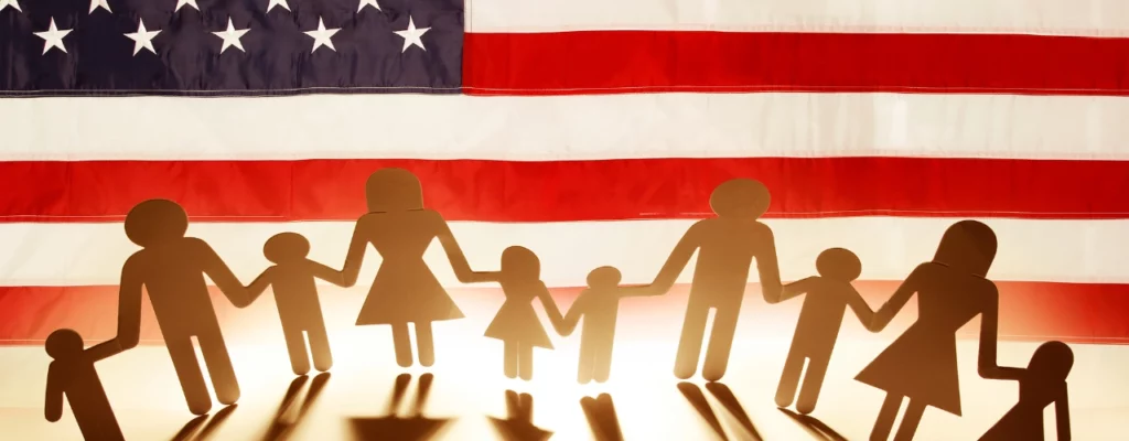 Bandera de USA con una familia de papel frente a ella, representando la petición familiar